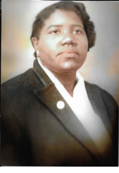 A head-and-shoulders portrait of a black woman with short hair. She wears a white blouse and a black jacket with lapels.